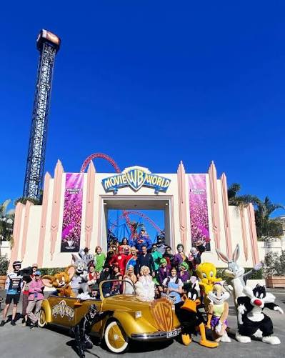 Movie World characters gathered at the park entrance with the gold WB car